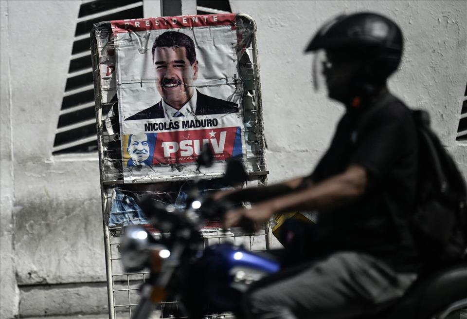 US Squeeze On Venezuela Won't Bring About Rapid Collapse Of Maduro  In Fact, It Might Boomerang On Washington A man rides past a poster of Venezuelan President Nicolas Maduro and an anti-tank barricade in Caracas on Oct. 28, 2025.          Juan Barreto/AFP via Getty Images
